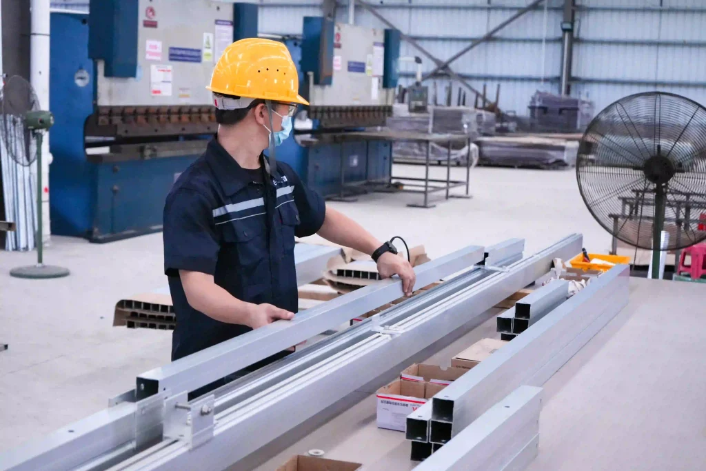 SR Solar skilled workers performing pre-assembly and quality testing on an aluminum solar mounting structure inside the SR Solar owned factory