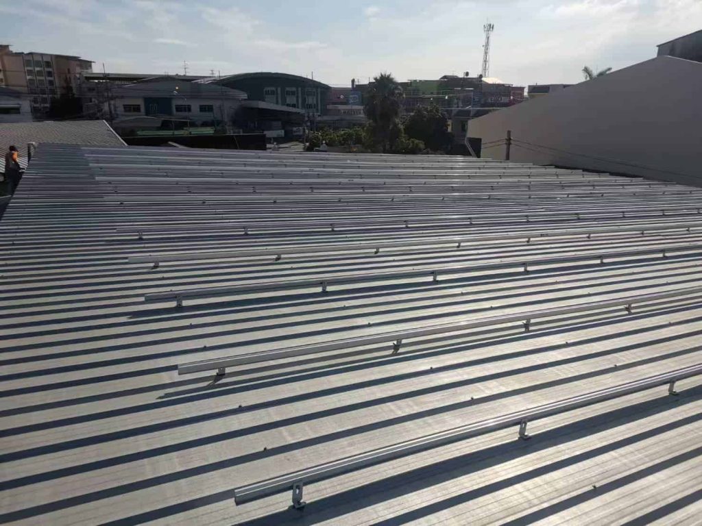 Long continuous lines of aluminum solar tracking brackets attached with the SR Solar L-feet configuration on an industrial corrugated sheet roof.