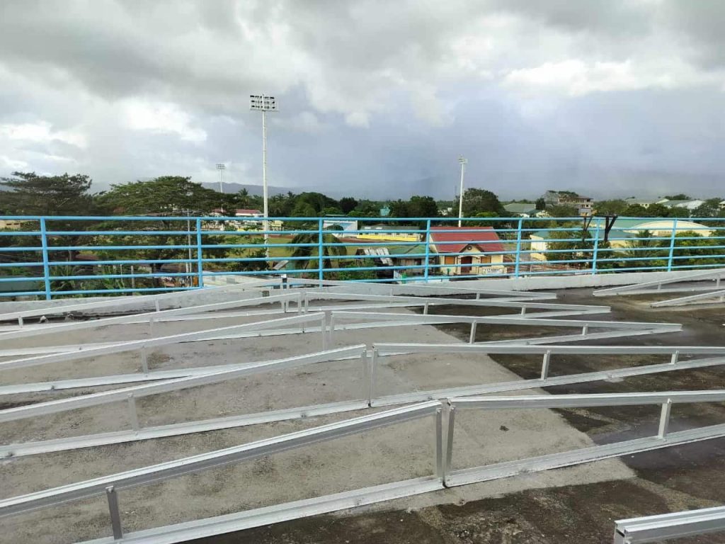Close-up alignment of SR Solar dual-slope triangle solar mount tracking rails near a rooftop safety perimeter.