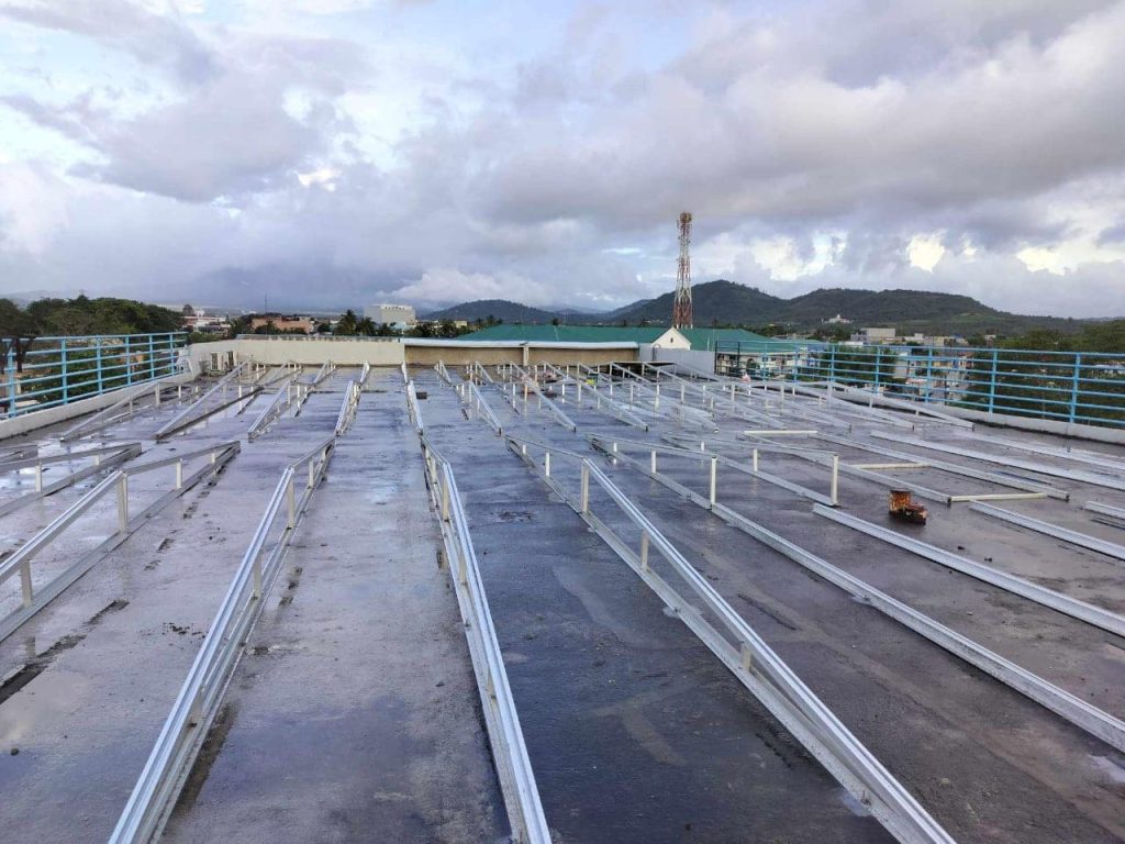 Longitudinal viewpoint of SR Solar aluminum dual-slope triangle racking system laid out across a large flat concrete roof.