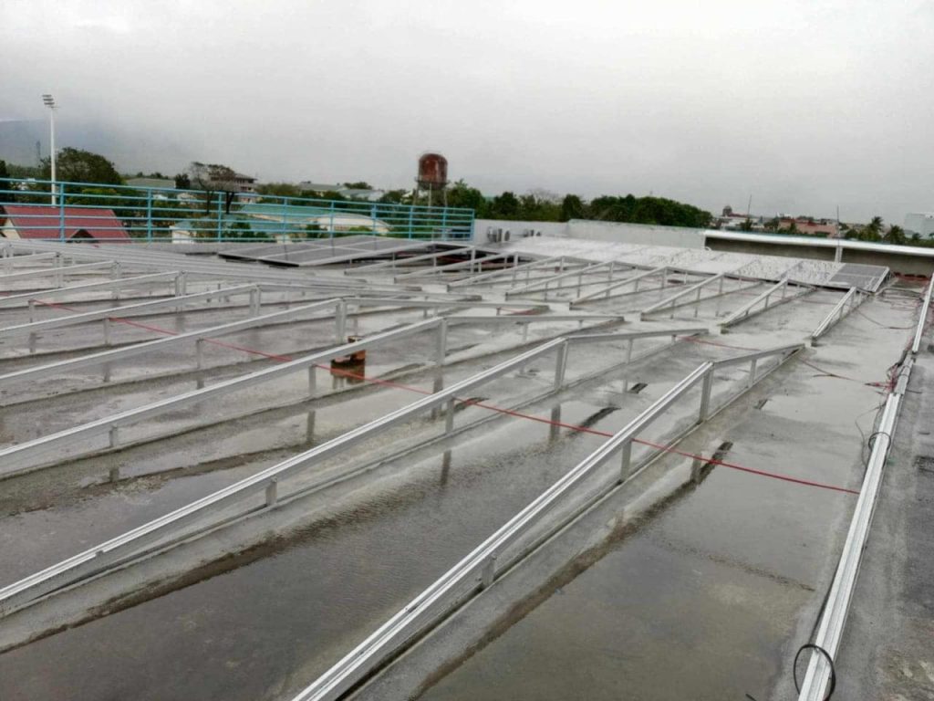 Rows of empty SR Solar east-west triangle aluminum framing structures installed on a flat concrete commercial roof.