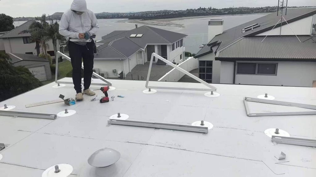 An installer assembling the AL6005-T5 aluminum triangle bracket base of an SR Solar flat roof mounting system on a TPO membrane.