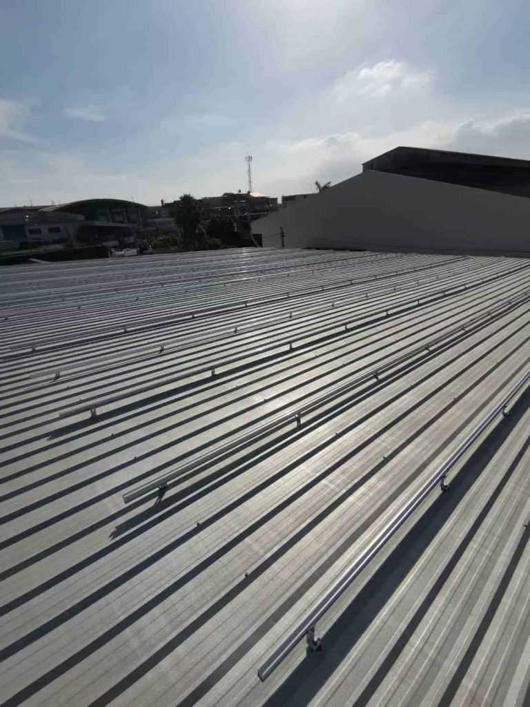 Upclose top-down perspective of anodized aluminum solar rails fastened with SR Solar waterproof L-feet brackets on a corrugated iron sheet.