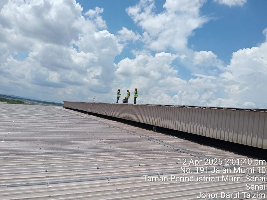 Engineers surveying a large industrial corrugated metal rooftop installation using the SR Solar L-feet mounting system in Malaysia.
