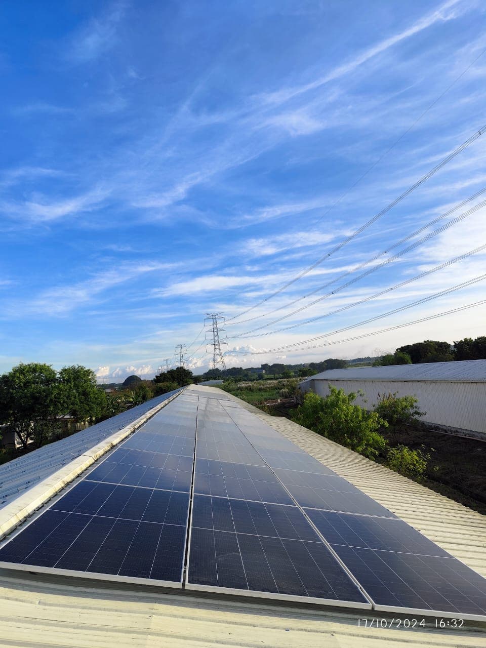 A long row of solar panels installed on a corrugated metal rooftop using the SR Solar L-feet mounting system under a clear sky.