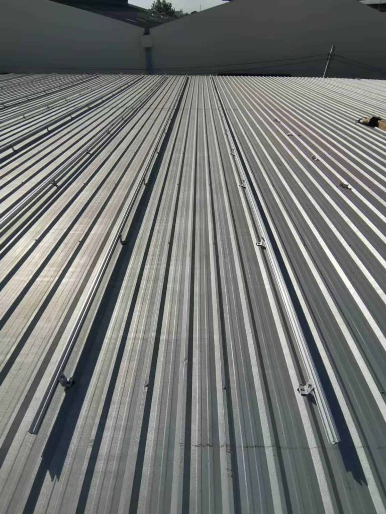 Long, straight lines of SR Solar aluminum mounting profiles ready for solar panel attachment on a corrugated metal warehouse roof.