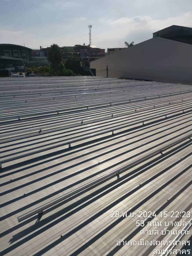Mid-range perspective of multiple solar rail rows secured with SR Solar L-feet brackets on a large industrial factory rooftop.