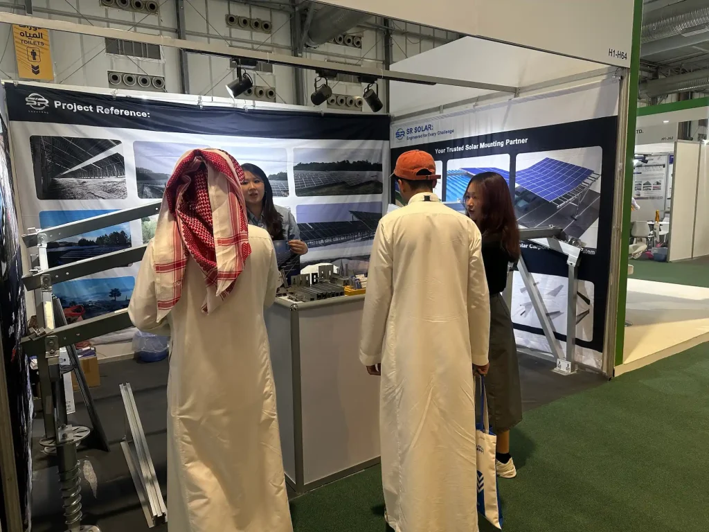 SR Solar team demonstrating OEM solar mounting brackets and ground screw samples to regional B2B clients at Saudi exhibition.